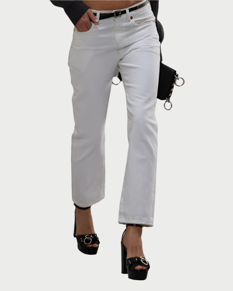 A person is shown walking against a white background, wearing R13's The Boyfriend Jean in Aerin White (premium cotton denim, relaxed fit), black high-heeled sandals, and holding a black clutch bag.