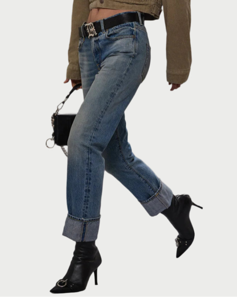 A person walks with a bag, wearing R13 Cuffed Romeo Jean Merrin Blue in a slim boyfriend fit, crafted from limited edition Italian selvedge denim.