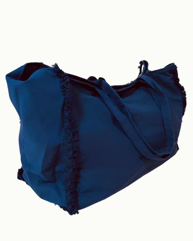 The DEBBIE KATZ Malan Beach Bag is a large, dark blue tote with frayed edges and two shoulder straps, shown against a plain white background.