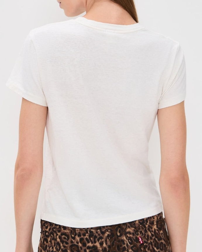 Woman wearing a white t-shirt and leopard print skirt on a plain background