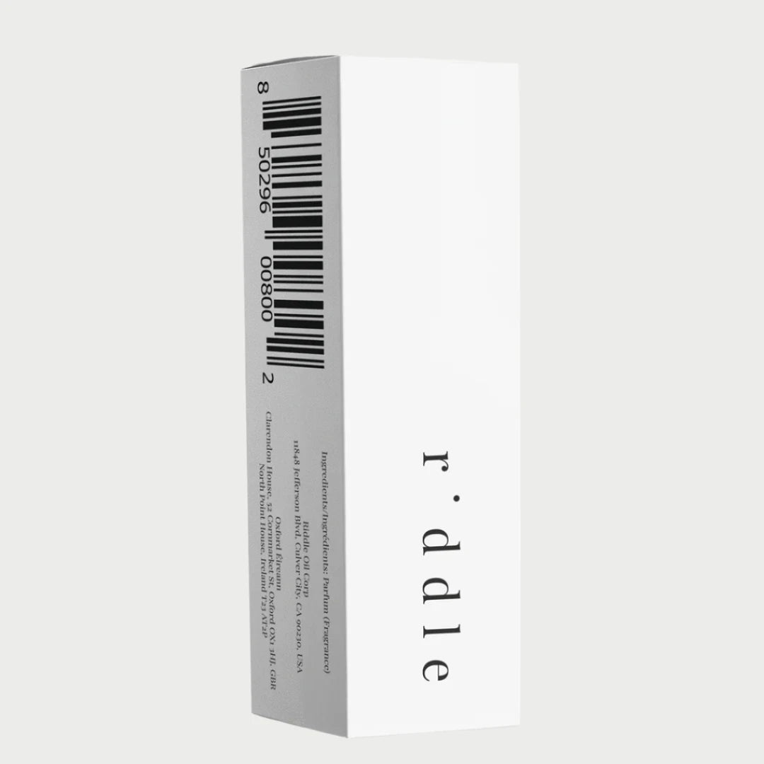 A white rectangular box featuring a vertical barcode and text on one side emanates a woody elegance. The front is adorned with "r·ddle" in lowercase letters, hinting at the mysterious blend of Riddle Oil 8ml: Ex within.
