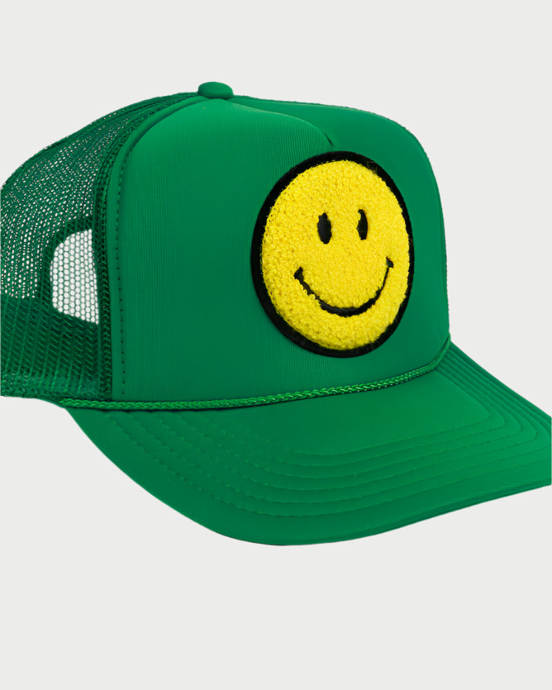 The LOCAL BEACH Smiley Patch Trucker Hat features a green mesh back, a chenille patch with a yellow smiley face, and a curved brim, offering a simple, cheerful design.