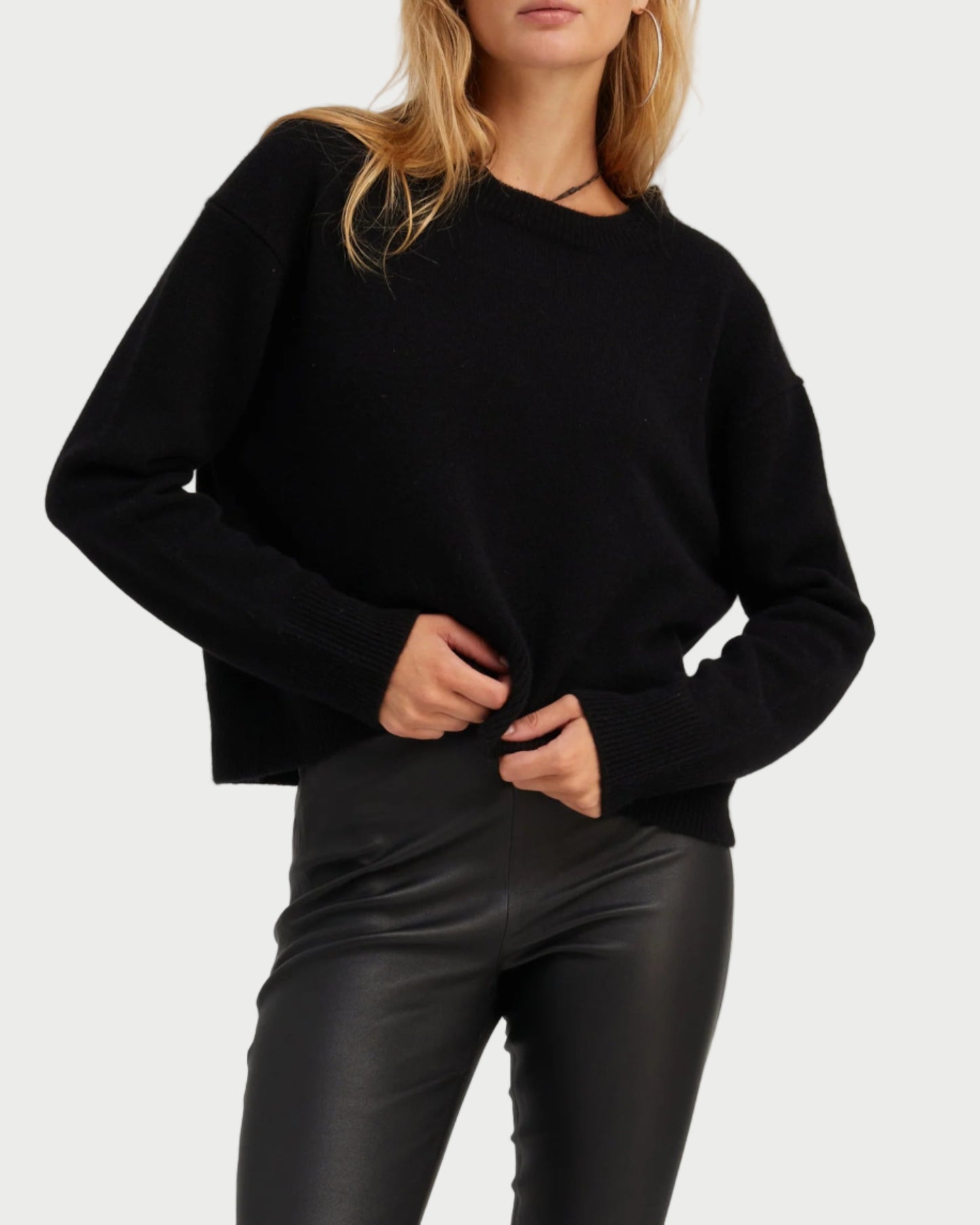 Woman wearing a black sweater and sunglasses on a light gray background