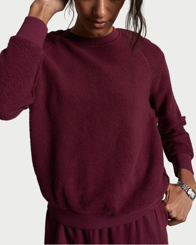 Woman wearing a maroon sweater against a plain background