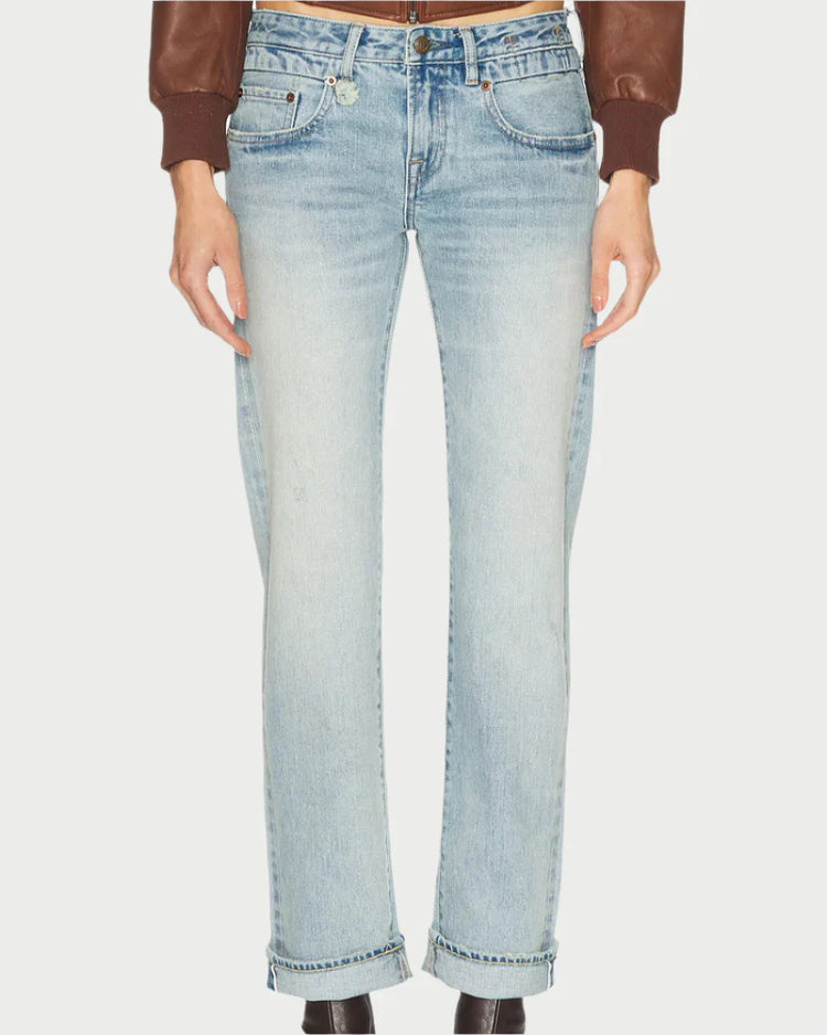 A person wearing light blue straight-leg jeans and a brown jacket, viewed from the front against a plain background. The jeans feature a classic five-pocket design and are accompanied by black ankle boots.
