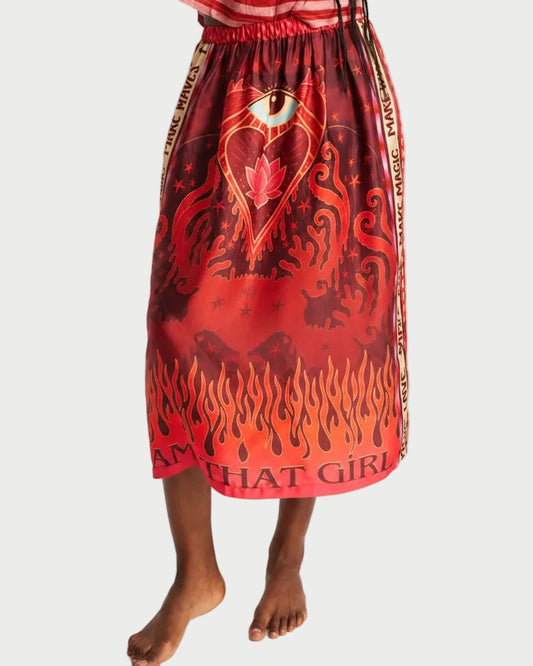 The ME369 Vanessa Midi Skirt Red Aura is a red skirt featuring a flaming-heart graphic, an eye, and flames, with the text “MAKE MAGIC” along the side and “AM THAT GIRL” along the hem.