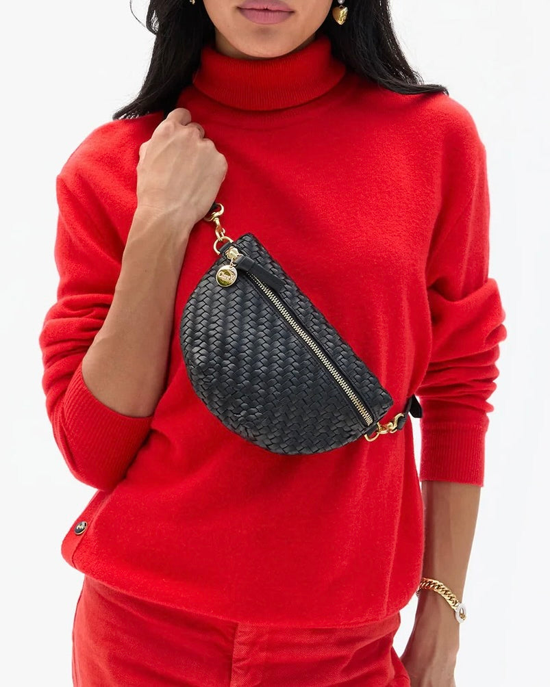 A black handwoven leather Clare V. Petite Fanny Black with gold hardware, worn across the chest as an adjustable crossbody bag.