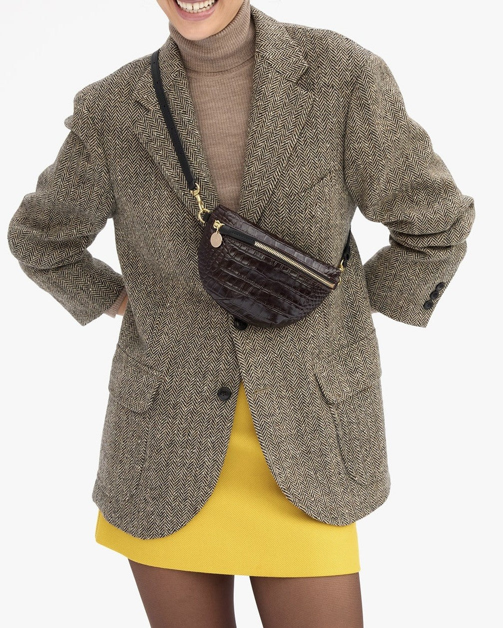 A person wears a Clare V. Petite Fanny Mahogany in dark brown crocodile-embossed leather crossbody over a tweed blazer.