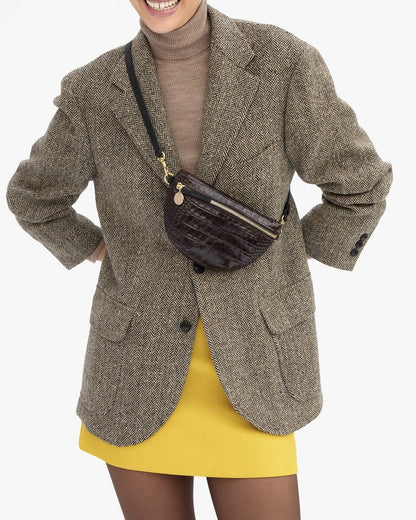 A person wears a Clare V. Petite Fanny Mahogany in dark brown crocodile-embossed leather crossbody over a tweed blazer.
