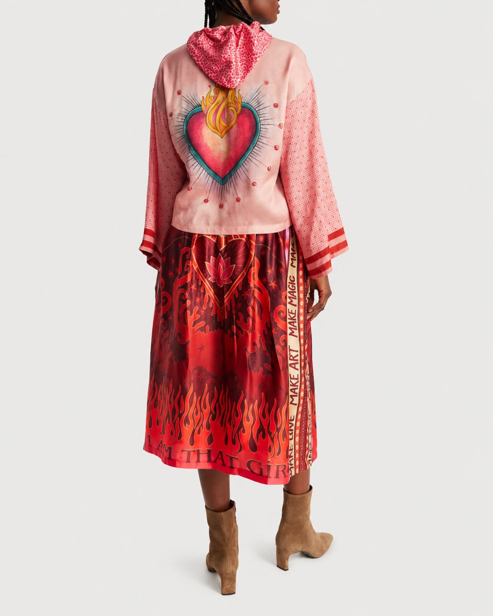 A person wearing a ME369 Mei Cropped Hoodie Red Aura, paired with a red mid-length skirt featuring a flame print and the text “MAKE ART” and “I AM THAT GIRL.”