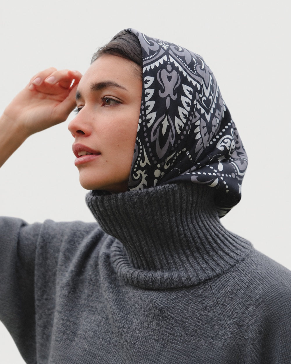 Maison Lecomte Flament Black bandana scarf worn as a headscarf with a dark sweater.