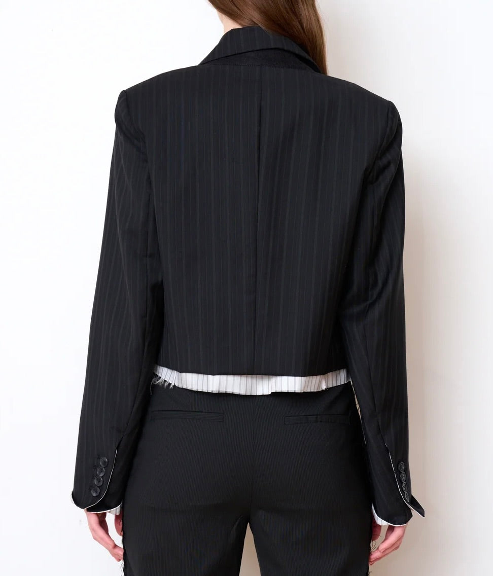 Back view of a black pinstriped WE-AR4 Cocktail Blazer Black Stripe in a cropped fit, layered over a white striped shirt and matching trousers.