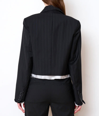 Back view of a black pinstriped WE-AR4 Cocktail Blazer Black Stripe in a cropped fit, layered over a white striped shirt and matching trousers.