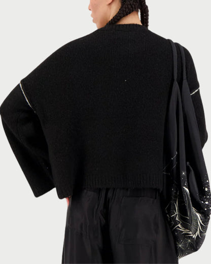 Person wearing a black sweater and pants with a white background