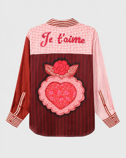 The ME369 Isabel Shirt Red Aura features a mix of red and pink patterns, a “Je t’aime” script across the back yoke, and a large heart and rose patch on the back.