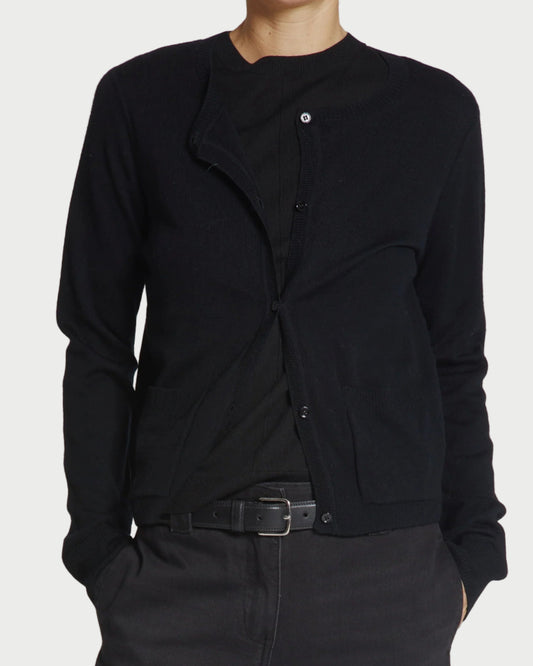 Person wearing a black cardigan and pants on a plain background