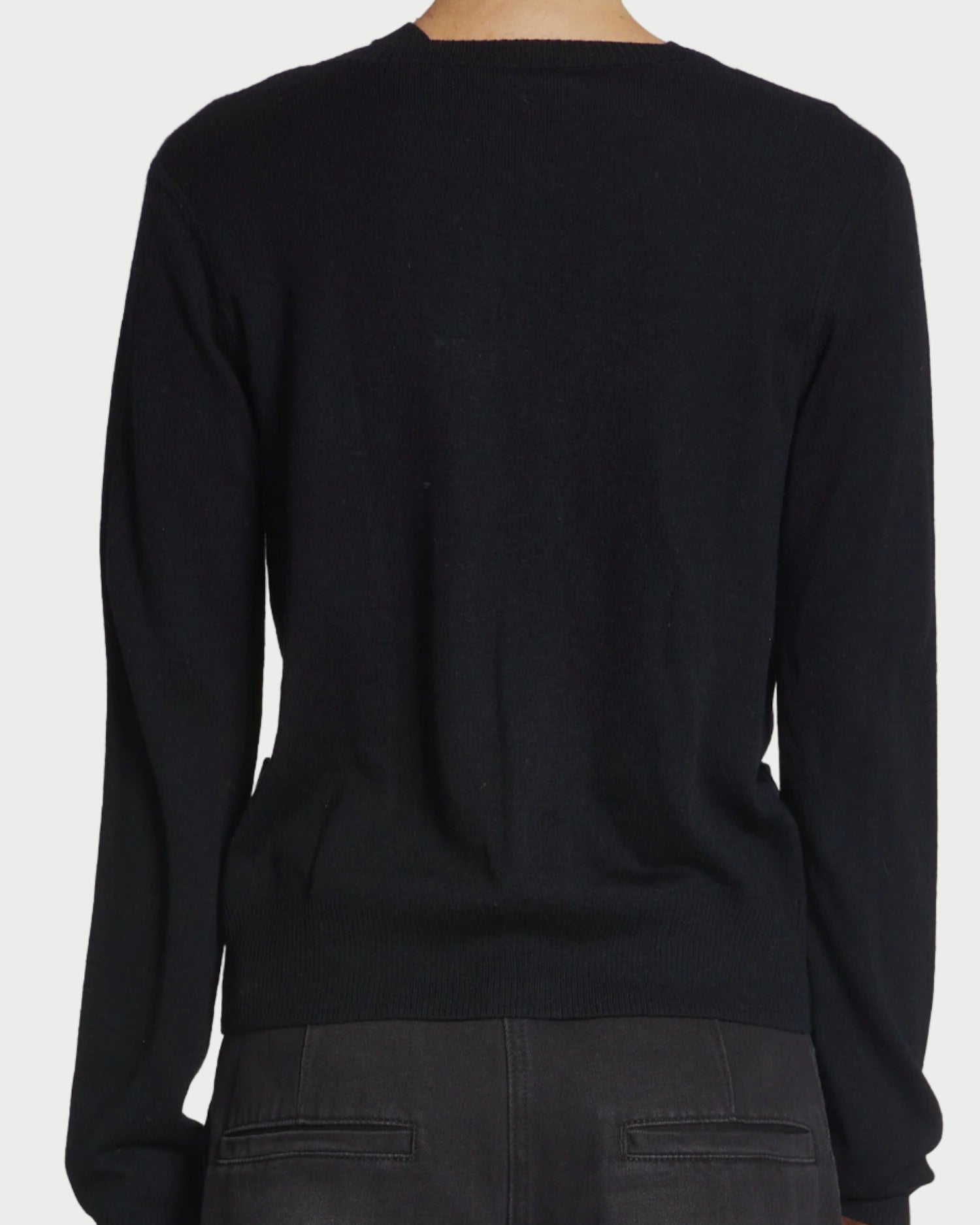 Black sweater worn by a person on a gray background