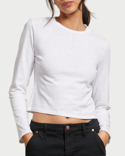 Person wearing a white long-sleeve top and black pants against a plain background