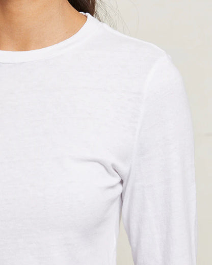 Close-up of a person wearing a white long-sleeve shirt against a neutral background