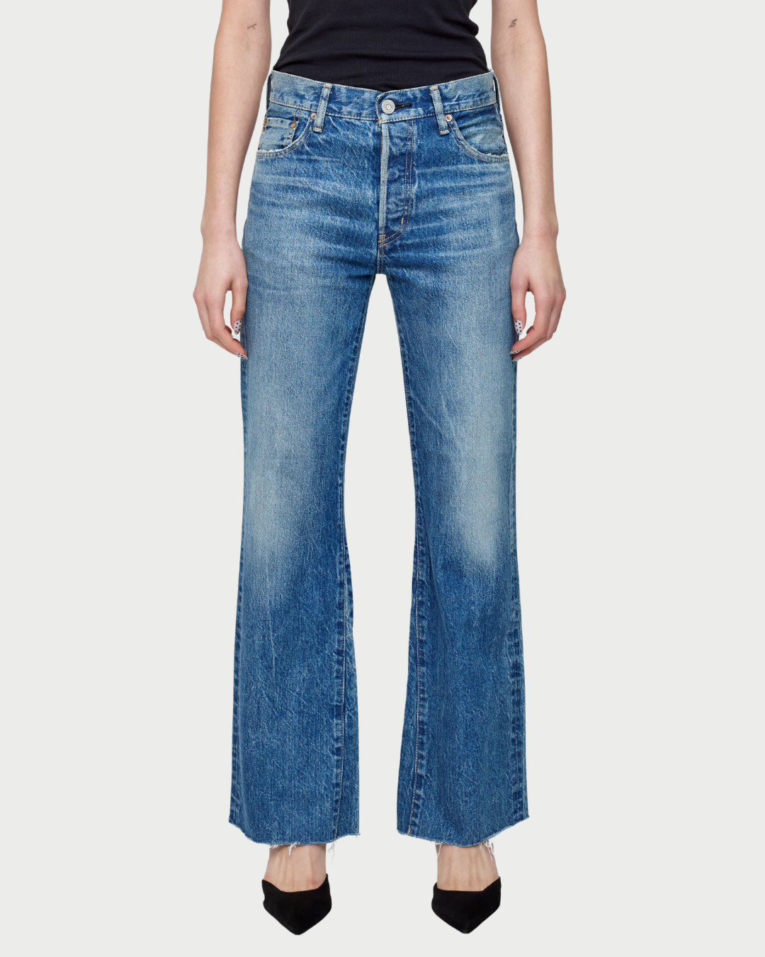 Person wearing blue flared jeans on a white background