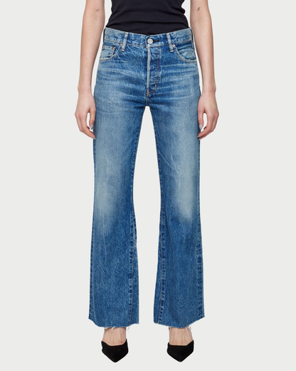 Person wearing blue flared jeans on a white background