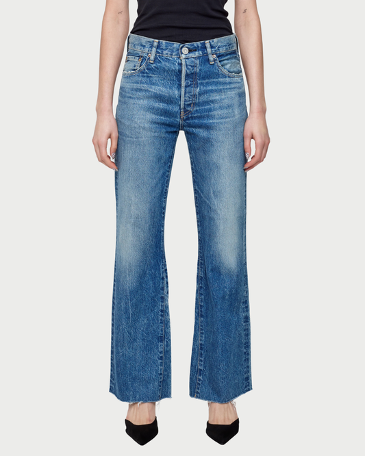 Person wearing blue flared jeans on a white background