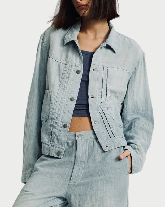 Woman wearing a light blue denim jacket and pants against a white background