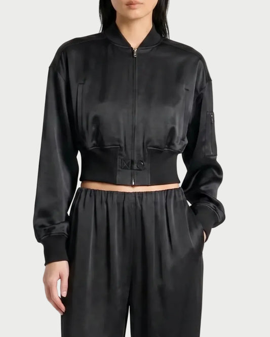 Wearing the Saint Art Hugh Bomber Jacket by Saint Art NY with matching high-waisted, loose black pants, a person stands against a plain light background.