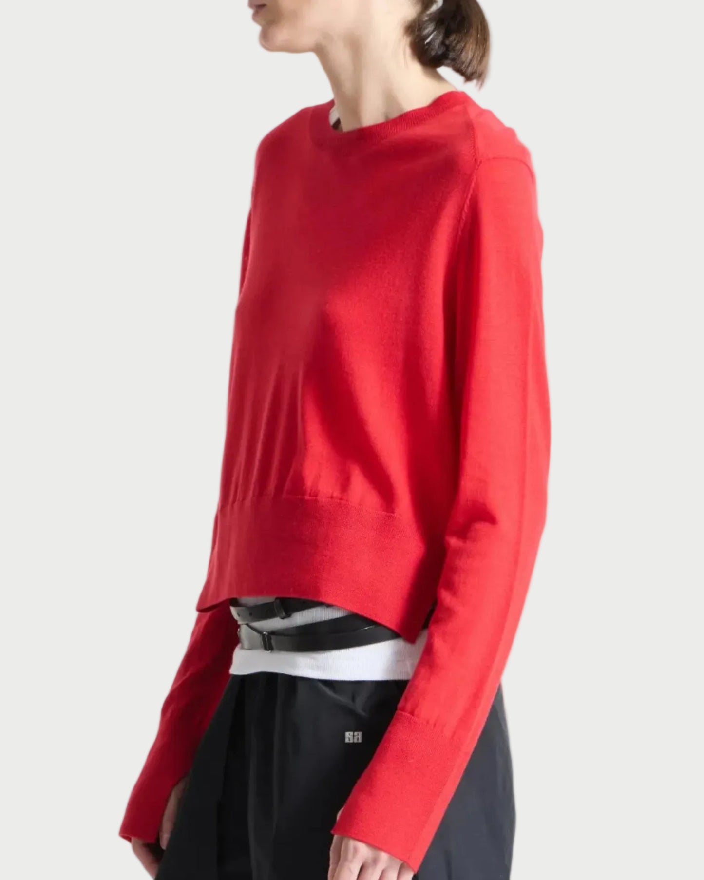 Person wearing a red sweater over a black and white striped shirt on a white background