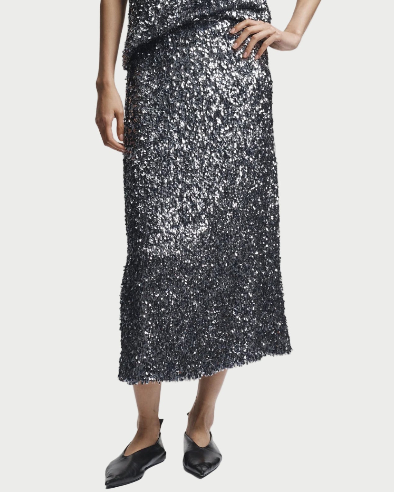 Person wearing a black sequin dress on a white background