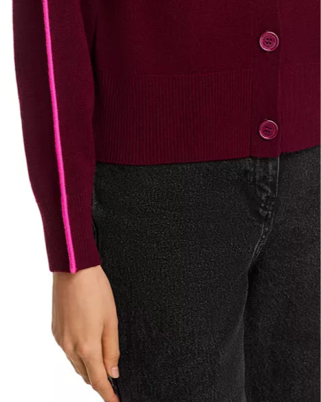 Close-up of a burgundy cardigan with pink trim worn by a person, on a white background.