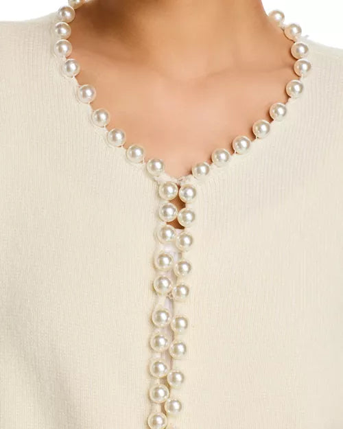 Pearl necklace draped over a person wearing a beige sweater