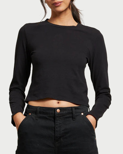 Woman wearing a black long-sleeve top and black pants against a neutral background