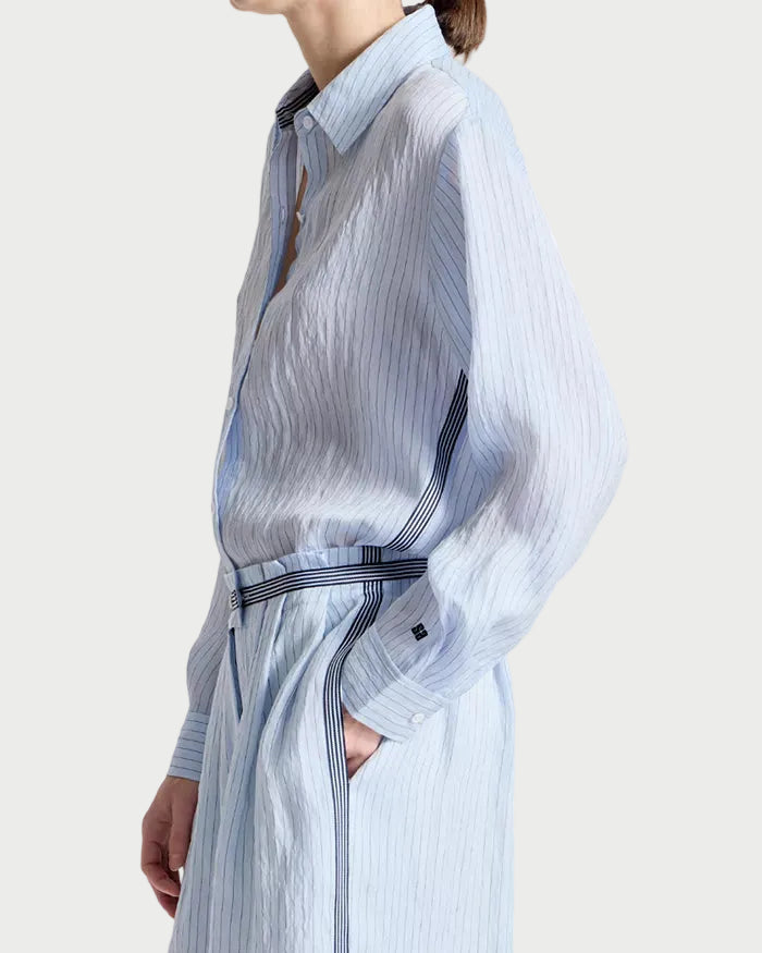 Person wearing a light blue striped dress with a belt on a white background
