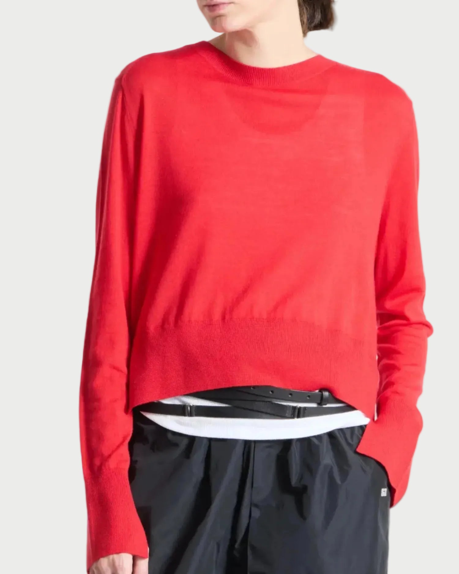 Person wearing a red sweater and black pants on a white background