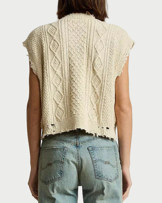 A person shown from the back wearing a cream cable-knit cropped sleeveless sweater and light blue jeans against a plain white background.
