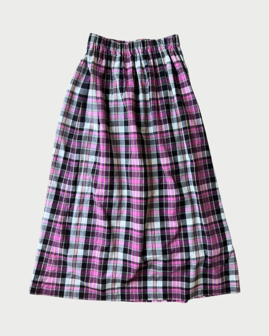The Tartan Plaid Skirt by A Friend Made features a pink, black, purple, and white plaid design with an elastic waistband. Sourced in Tokyo, it’s shown flat on a white background.