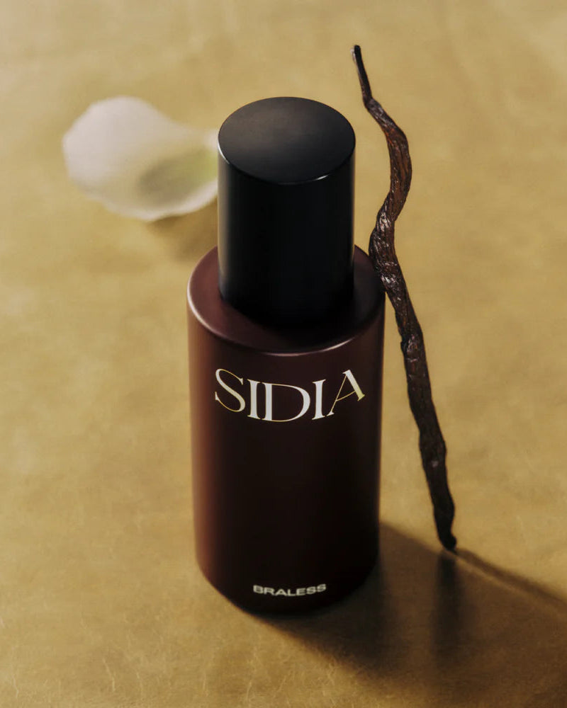 Bottle of Sidia perfume with a vanilla bean on a beige background