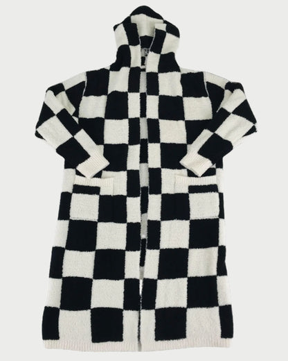 The LOCAL BEACH Black Checker Luxe Robe is a long, hooded robe with a black and white checkerboard pattern, front pockets, and long sleeves—perfect for cozy lounging on any relaxing day.