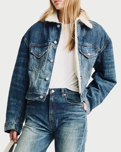 Person wearing a denim jacket and jeans holding a white tote bag on a light gray background