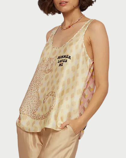 Woman wearing a yellow lace top and beige pants against a white background