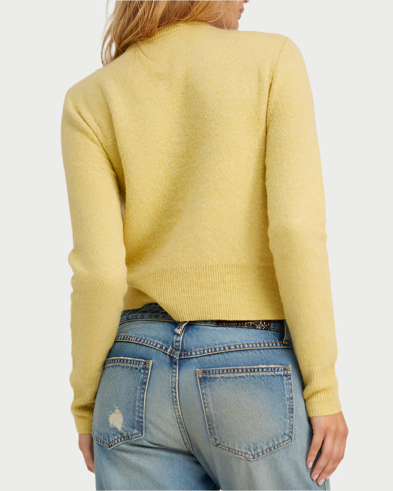 Seen from behind, a person with long hair wears a SPRWMN Baby Cashmere Cardigan in light yellow and distressed blue jeans featuring a slightly worn look with a rip on the pocket.