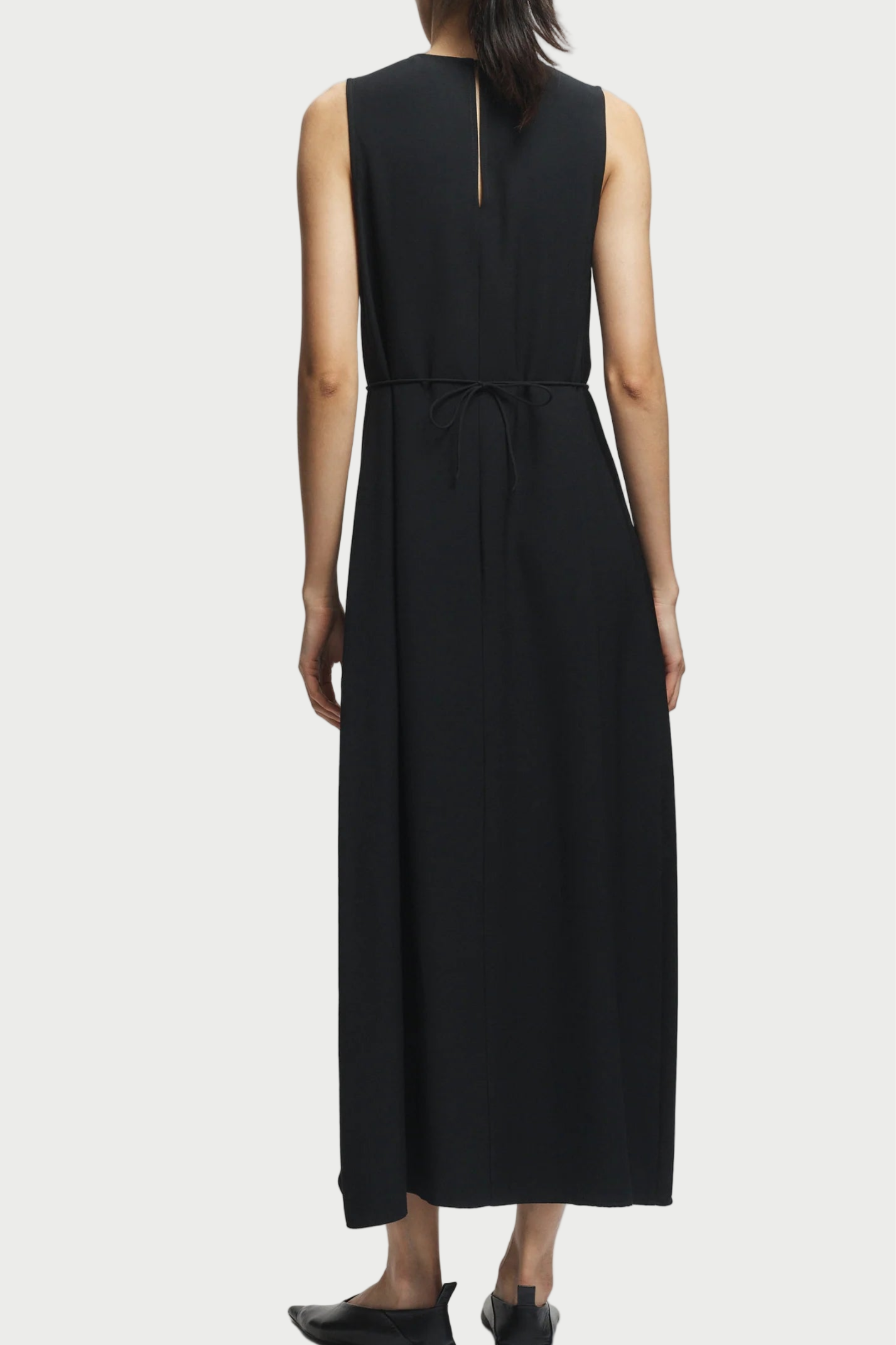 Black sleeveless dress worn by a person on a white background