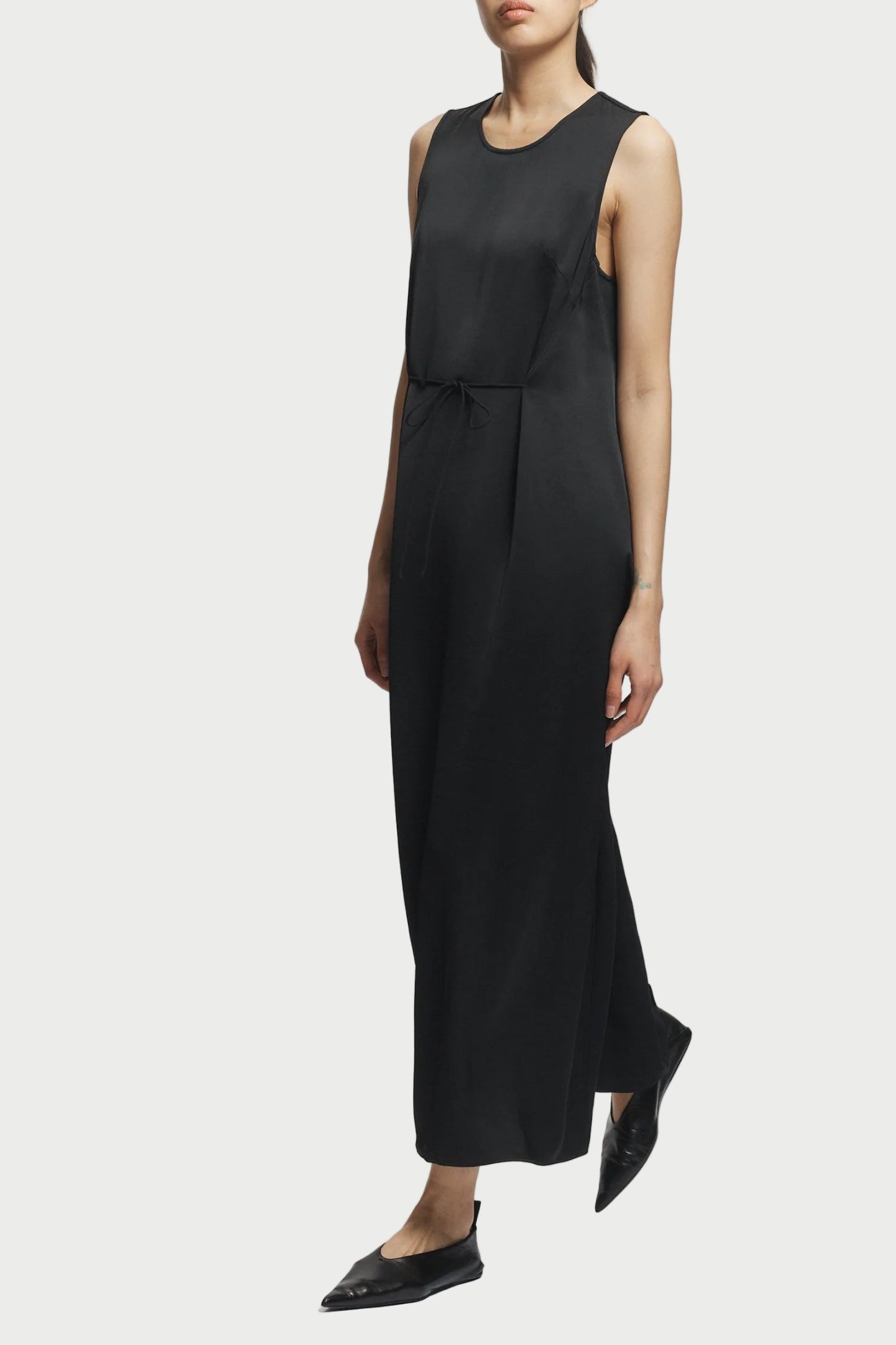 Black sleeveless dress worn by a person on a white background