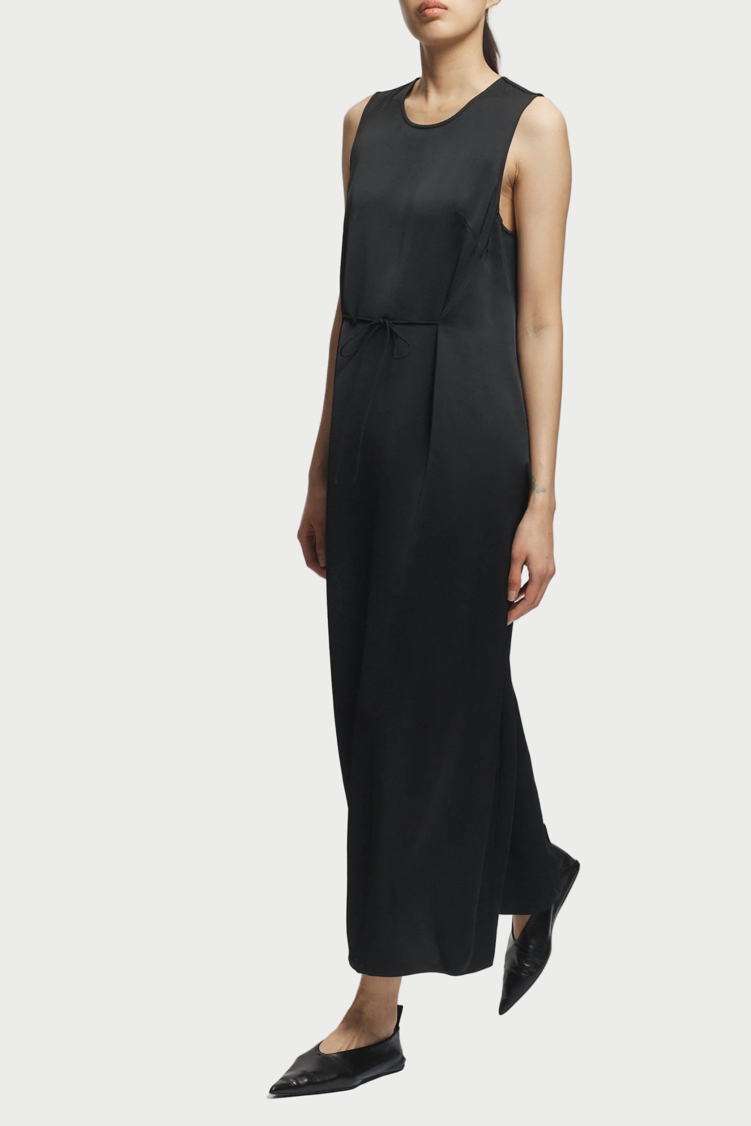 Black sleeveless dress worn by a person on a white background