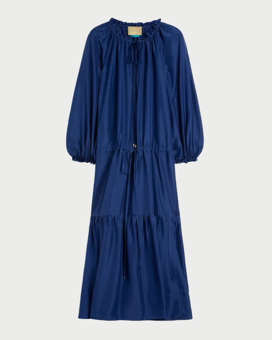 The Momoni Viento Dress by Momoni is a loose-fitting, ankle-length navy blue habutai silk dress with long sleeves, a ruffled neckline, drawstring waist, and gathered skirt, shown on a plain white background.