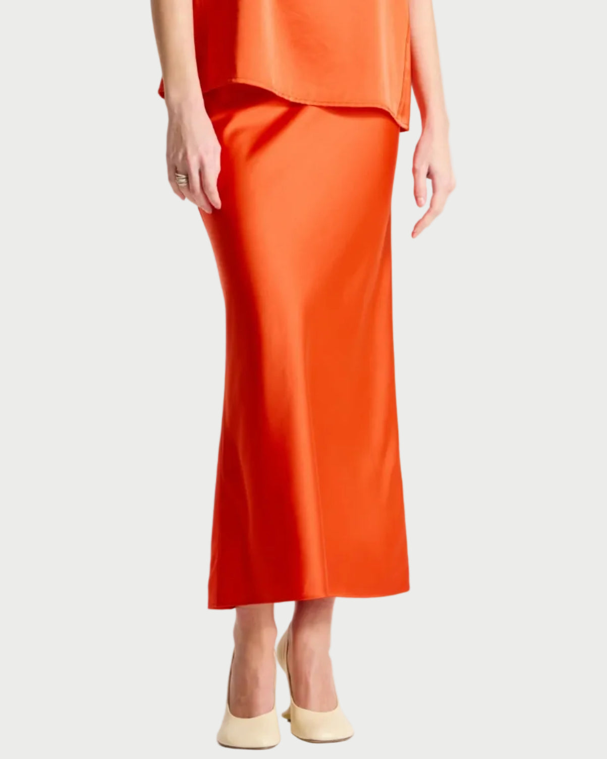 Person wearing an orange sleeveless top and skirt set on a white background