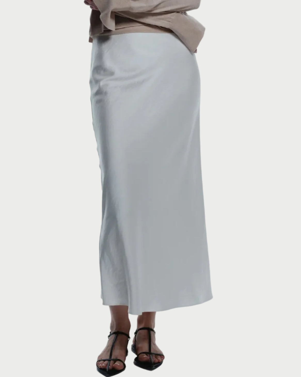 Woman wearing a beige sweater and white skirt on a white background