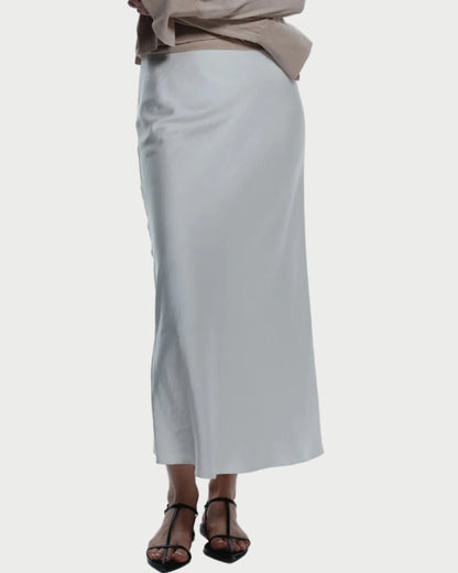 Woman wearing a beige sweater and white skirt on a white background