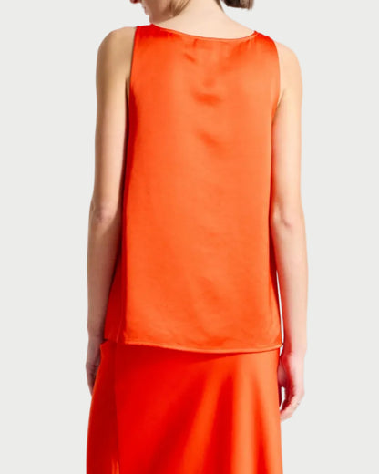 Person wearing a bright orange sleeveless top and skirt set on a white background